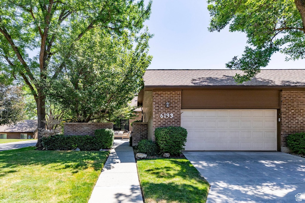 6193 S 1050 E Unit 61, Salt Lake City, UT 84121 - view of front facade with brick siding, concrete driveway, a garage, and a front lawn