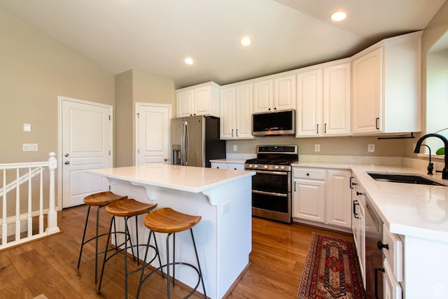 552 E Sunset Stream Way, Draper, UT 84020 - kitchen with appliances with stainless steel finishes, vaulted ceiling, wood finished floors, a kitchen bar, and white cabinetry
