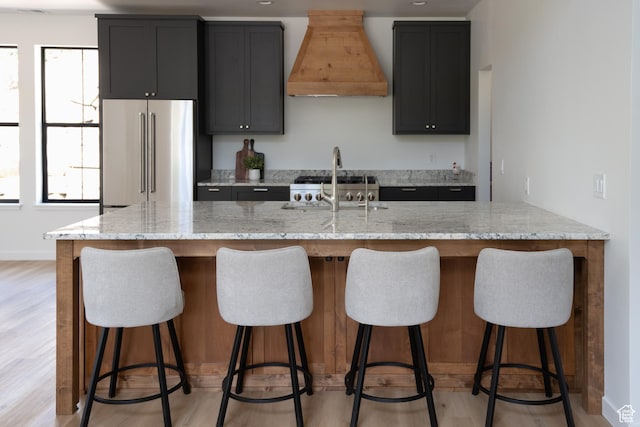 2640 W State Road 32, Peoa, UT 84061 - kitchen featuring high end fridge, custom exhaust hood, light stone countertops, and light wood-style flooring