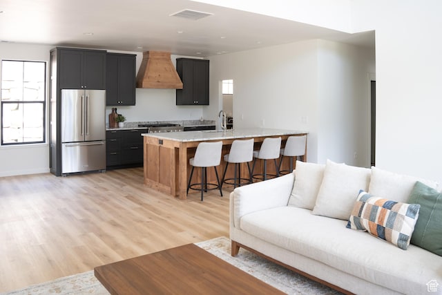 2640 W State Road 32, Peoa, UT 84061 - kitchen featuring high end refrigerator, custom range hood, a breakfast bar, light wood-style floors, and dark cabinetry