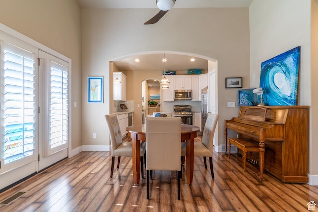 10296 S Salmon Dr, South Jordan, UT 84095 - dining room featuring arched walkways, a ceiling fan, wood finished floors, healthy amount of natural light, and a high ceiling