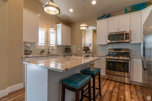 10296 S Salmon Dr, South Jordan, UT 84095 - kitchen featuring stainless steel appliances, dark wood finished floors, white cabinets, decorative backsplash, and a center island