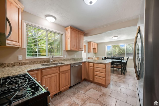 8916 S Cobble Crest Ln E, Sandy, UT 84093 - kitchen featuring appliances with stainless steel finishes, light stone counters, light brown cabinetry, a peninsula, and a textured ceiling