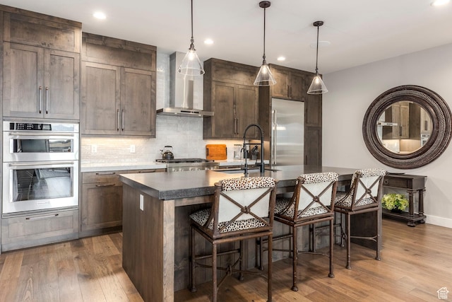 855 E Klaim Dr, Hideout, UT 84036 - kitchen with wall chimney exhaust hood, stainless steel appliances, dark wood-style flooring, a center island with sink, and recessed lighting