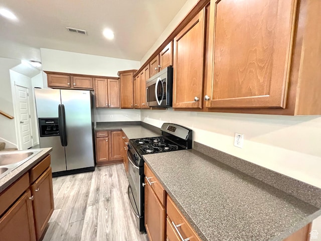 3794 W Angelica Ct, South Jordan, UT 84095 - kitchen featuring stainless steel appliances, brown cabinetry, light wood finished floors, dark countertops, and vaulted ceiling