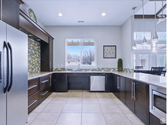3794 W Angelica Ct, South Jordan, UT 84095 - kitchen with stainless steel appliances, decorative backsplash, light tile patterned floors, light countertops, and dark brown cabinetry