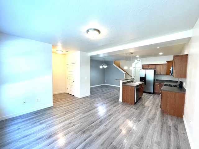 3794 W Angelica Ct, South Jordan, UT 84095 - kitchen with stainless steel appliances, open floor plan, a chandelier, a center island with sink, and light wood-type flooring