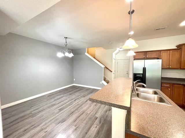3794 W Angelica Ct, South Jordan, UT 84095 - kitchen with stainless steel fridge, brown cabinetry, wood finished floors, hanging light fixtures, and a chandelier