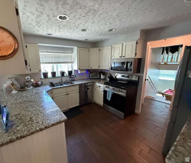 1012 W 3550 N, Pleasant View, UT 84414 - kitchen featuring appliances with stainless steel finishes, dark wood-style flooring, light stone countertops, white cabinetry, and a textured ceiling