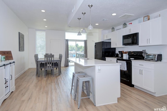 1690 S 225 W, Clearfield, UT 84015 - kitchen featuring black appliances, light wood finished floors, white cabinets, recessed lighting, and a center island with sink