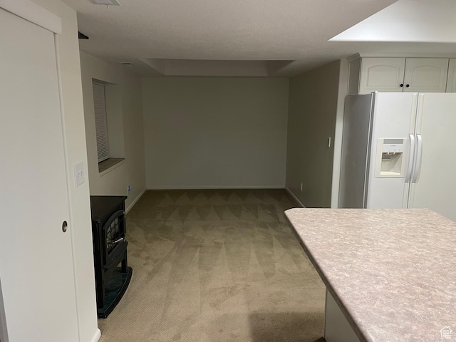 484 N 300 W, Logan, UT 84321 - kitchen featuring white fridge with ice dispenser, light colored carpet, a wood stove, white cabinetry, and light countertops