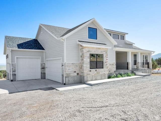 2423 W Cedarline Loop, Stockton, UT 84071 - view of front of property with driveway, stone siding, a porch, a shingled roof, and a garage