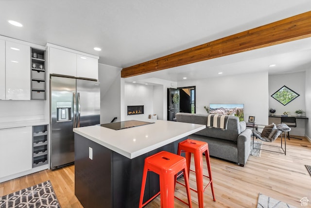 947 Northstar Dr, Park City, UT 84060 - kitchen with stainless steel fridge, white cabinetry, a glass covered fireplace, black electric stovetop, and light wood-style floors