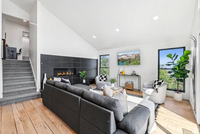 947 Northstar Dr, Park City, UT 84060 - living area with light wood-type flooring, high vaulted ceiling, recessed lighting, a tiled fireplace, and stairs