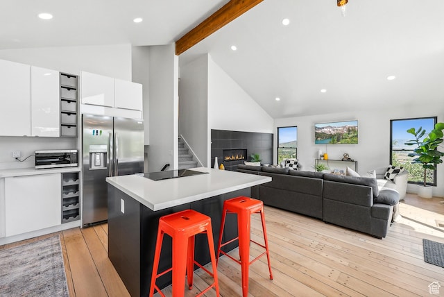 947 Northstar Dr, Park City, UT 84060 - kitchen with stainless steel fridge, white cabinetry, a kitchen bar, a kitchen island, and high vaulted ceiling