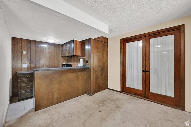 4445 Fillmore Ave, Ogden, UT 84403 - kitchen featuring french doors, light colored carpet, a textured ceiling, brown cabinets, and wooden walls