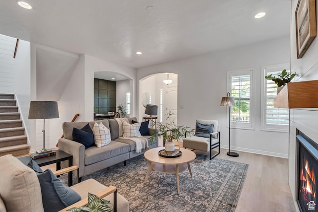 10741 S Topview Rd, South Jordan, UT 84095 - living area with wood finished floors, arched walkways, stairway, a lit fireplace, and recessed lighting