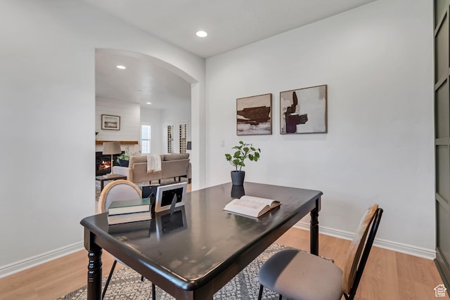 10741 S Topview Rd, South Jordan, UT 84095 - dining room with arched walkways, light wood-style floors, a lit fireplace, recessed lighting, and an office area