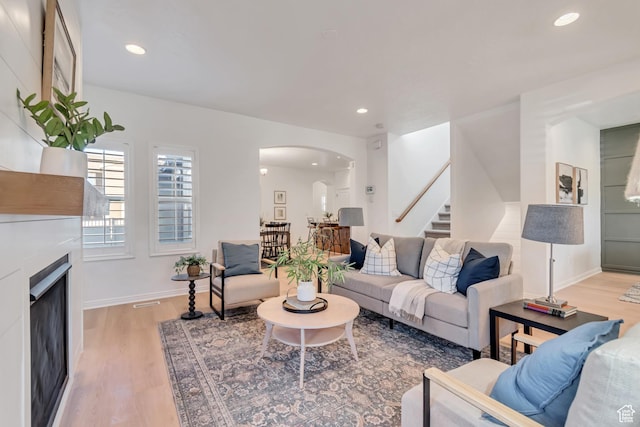10741 S Topview Rd, South Jordan, UT 84095 - living room featuring arched walkways, stairs, wood finished floors, recessed lighting, and a fireplace