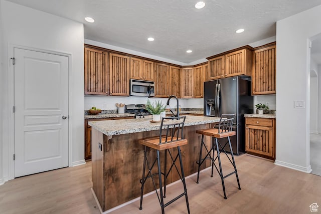 10741 S Topview Rd, South Jordan, UT 84095 - kitchen featuring stainless steel appliances, light wood-style floors, recessed lighting, a breakfast bar, and a kitchen island with sink
