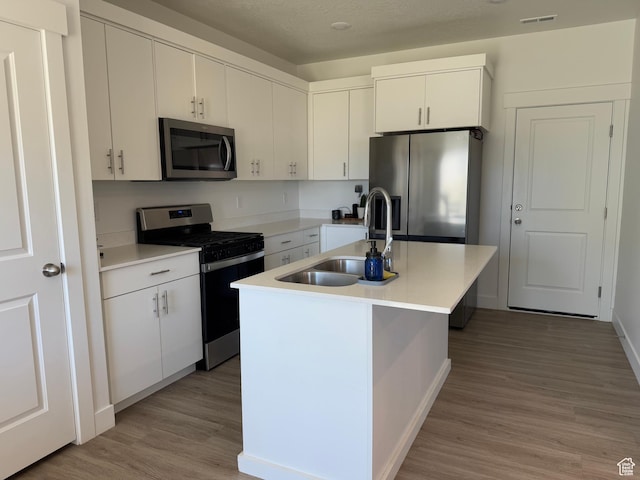 931 W 910 N, Tremonton, UT 84337 - kitchen with appliances with stainless steel finishes, light wood finished floors, light countertops, a center island with sink, and white cabinets
