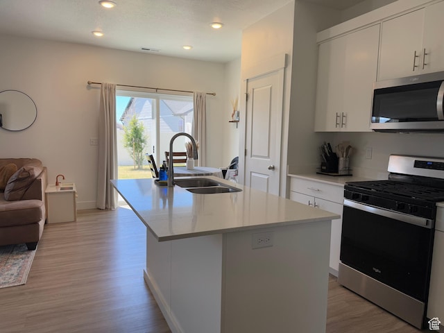 931 W 910 N, Tremonton, UT 84337 - kitchen with appliances with stainless steel finishes, light wood-style flooring, a center island with sink, light countertops, and white cabinets