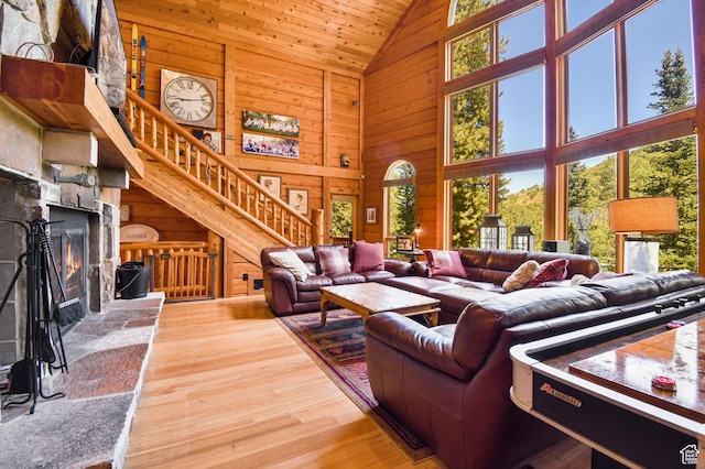 8581 Shingle Mill Dr, Oakley, UT 84055 - living area featuring high vaulted ceiling, wooden walls, wood finished floors, stairway, and a stone fireplace