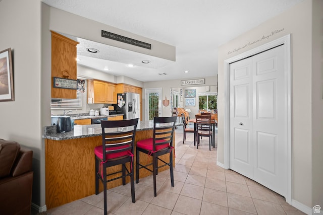 845 N Valley View Dr Unit 917, St George, UT 84770 - kitchen with stainless steel refrigerator with ice dispenser, light tile patterned floors, a peninsula, a kitchen breakfast bar, and dark stone counters