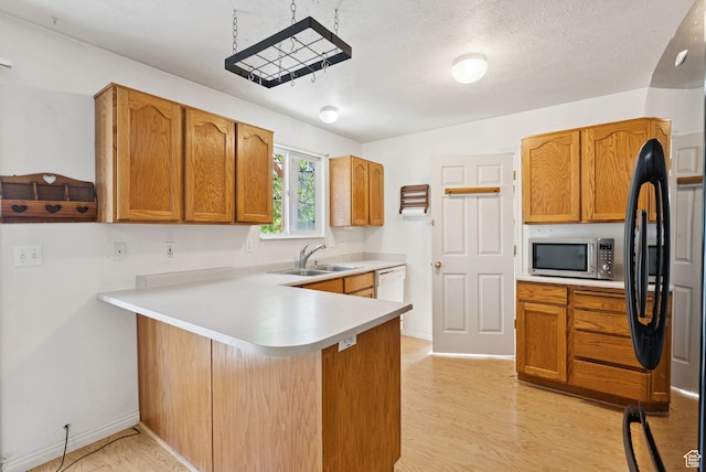 2970 W Shadow Park Dr, West Valley City, UT 84119 - kitchen featuring stainless steel microwave, a peninsula, freestanding refrigerator, light countertops, and light wood-style flooring