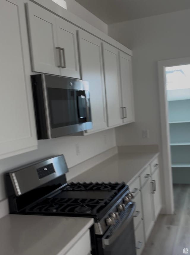6178 S Kelly Ln, St George, UT 84790 - kitchen with stainless steel appliances, white cabinetry, light countertops, and light wood-type flooring