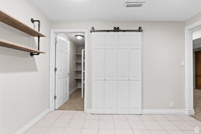 763 W 100 N, Hurricane, UT 84737 - unfurnished bedroom featuring light carpet, light tile patterned floors, a closet, and a barn door