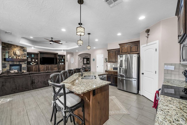 3334 W 2700 S, Hurricane, UT 84737 - kitchen with appliances with stainless steel finishes, arched walkways, a ceiling fan, dark brown cabinetry, and a kitchen breakfast bar
