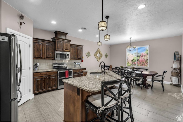 3334 W 2700 S, Hurricane, UT 84737 - kitchen featuring stainless steel appliances, tasteful backsplash, a kitchen breakfast bar, light stone countertops, and a textured ceiling