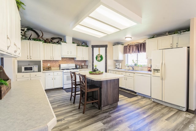 5375 N Canal Rd, Lapoint, UT 84039 - kitchen with white appliances, wood finished floors, a breakfast bar, and white cabinetry