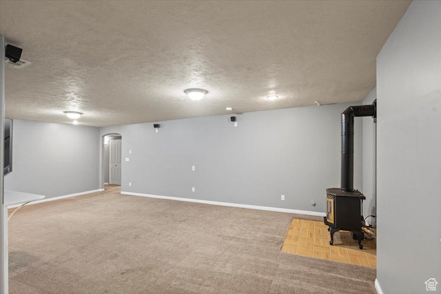 845 S 1150 E, Preston, ID 83263 - basement with arched walkways, a textured ceiling, a wood stove, and carpet flooring