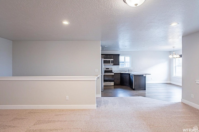 124 N Peach St, Santaquin, UT 84655 - kitchen with stainless steel appliances, dark carpet, a textured ceiling, a chandelier, and light countertops