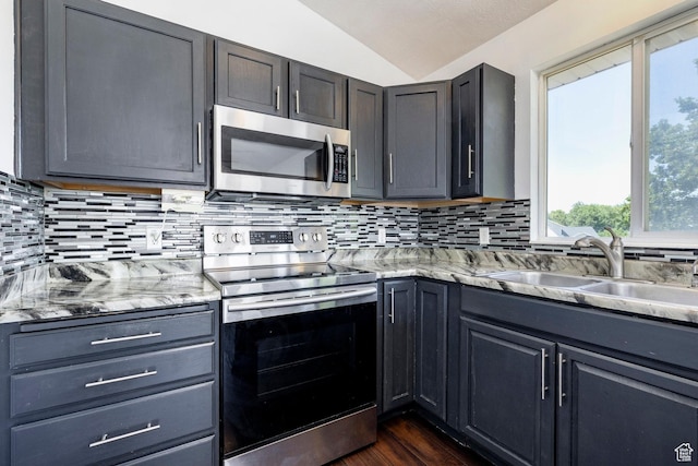 902 W 4200 S, Riverdale, UT 84405 - kitchen with appliances with stainless steel finishes, vaulted ceiling, tasteful backsplash, light stone counters, and dark wood-type flooring