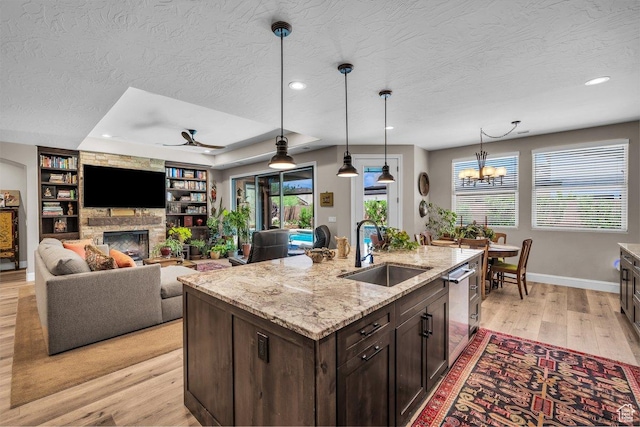 2751 S 3970 W, Hurricane, UT 84737 - kitchen featuring light wood finished floors, dark brown cabinets, a fireplace, a textured ceiling, and dishwasher