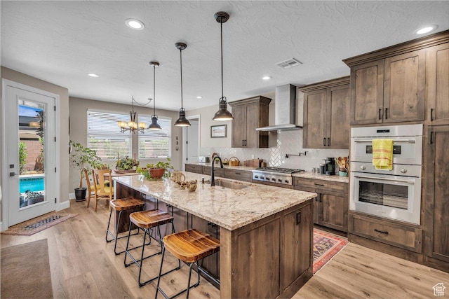 2751 S 3970 W, Hurricane, UT 84737 - kitchen featuring wall chimney exhaust hood, appliances with stainless steel finishes, light wood-style flooring, a breakfast bar, and recessed lighting