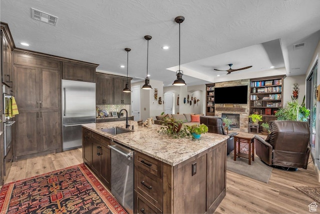 2751 S 3970 W, Hurricane, UT 84737 - kitchen with appliances with stainless steel finishes, ceiling fan, light wood-style flooring, a fireplace, and light stone counters