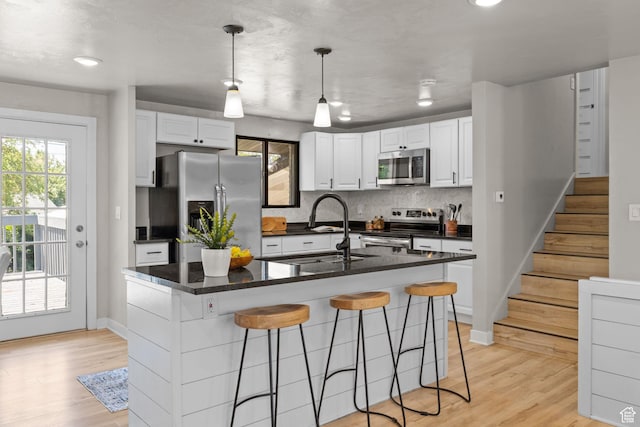2111 W 5800 S, Roy, UT 84067 - kitchen featuring appliances with stainless steel finishes, a kitchen breakfast bar, white cabinets, decorative backsplash, and light wood-style flooring