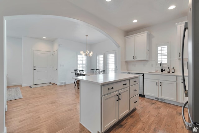 6427 W Arranmore Dr, South Jordan, UT 84009 - kitchen with arched walkways, a chandelier, light wood finished floors, recessed lighting, and white cabinets