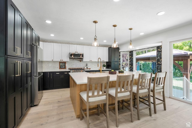 2038 W 8970 S, West Jordan, UT 84088 - kitchen featuring stainless steel microwave, light countertops, a kitchen breakfast bar, freestanding refrigerator, and tasteful backsplash
