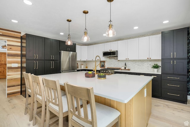 2038 W 8970 S, West Jordan, UT 84088 - kitchen with stainless steel appliances, light wood finished floors, recessed lighting, a kitchen bar, and tasteful backsplash