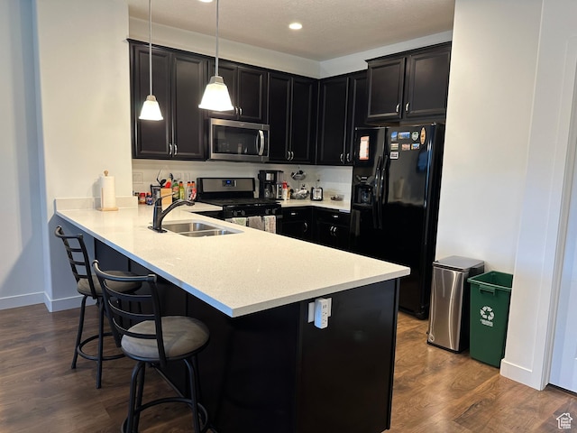 981 W Cyan Valley Way, Bluffdale, UT 84065 - kitchen featuring stainless steel microwave, black refrigerator with ice dispenser, range with gas stovetop, a kitchen breakfast bar, and a peninsula