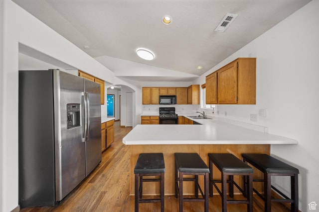 5317 N 2700 W, Cedar City, UT 84721 - kitchen with black appliances, lofted ceiling, a peninsula, arched walkways, and brown cabinetry