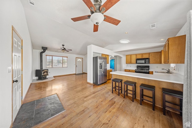 5317 N 2700 W, Cedar City, UT 84721 - kitchen with black appliances, lofted ceiling, a wood stove, light countertops, and a ceiling fan