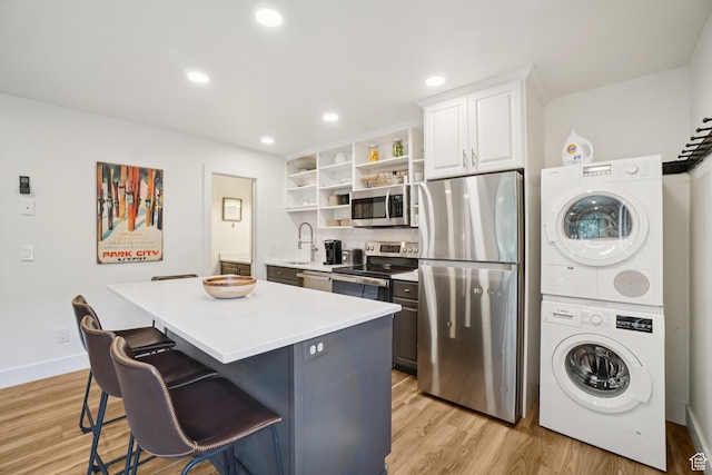 2025 Canyons Resort Dr Unit I1, Park City, UT 84098 - kitchen featuring stainless steel appliances, estacked washer and dryer, open shelves, a kitchen island, and a breakfast bar