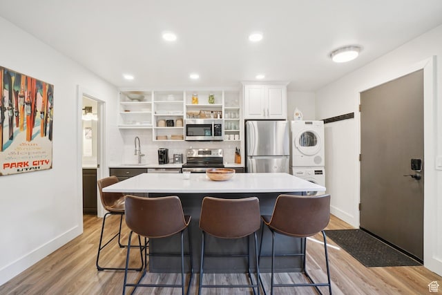 2025 Canyons Resort Dr Unit I1, Park City, UT 84098 - kitchen featuring stainless steel appliances, stacked washer and clothes dryer, open shelves, a breakfast bar area, and a kitchen island