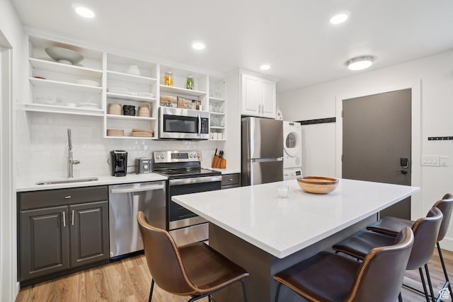 2025 Canyons Resort Dr Unit I1, Park City, UT 84098 - kitchen featuring stainless steel appliances, stacked washer / dryer, open shelves, a breakfast bar, and light wood-style floors